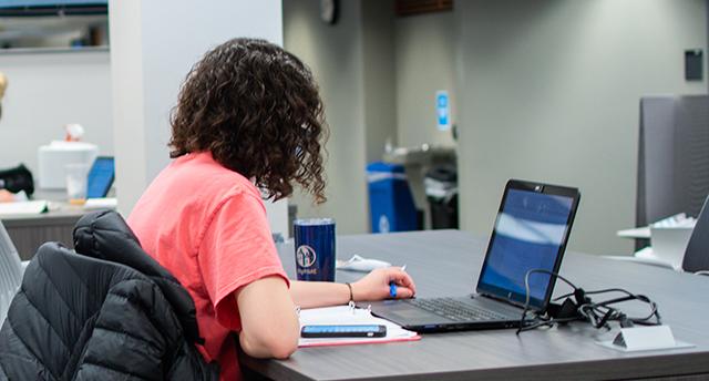 Photo of a student working in Cowles Library on her laptop